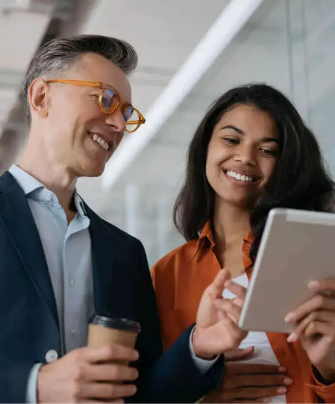 Hospitality executive and employee looking at digital tablet while smiling