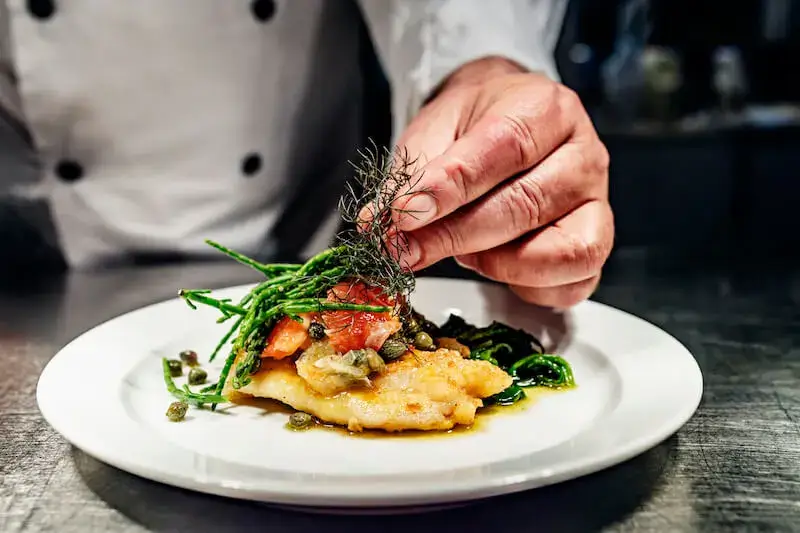 Close-up of a chef garnishing a dish