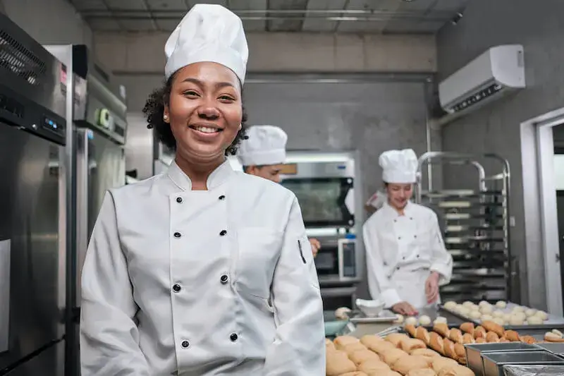 Confident culinary school graduate in professional kitchen uniform.