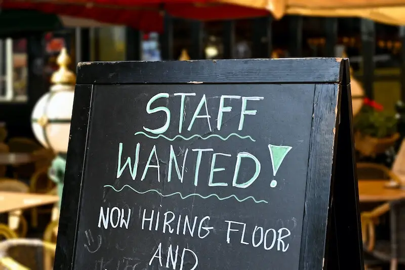 Chalkboard sign reading Staff Wanted outside a restaurant
